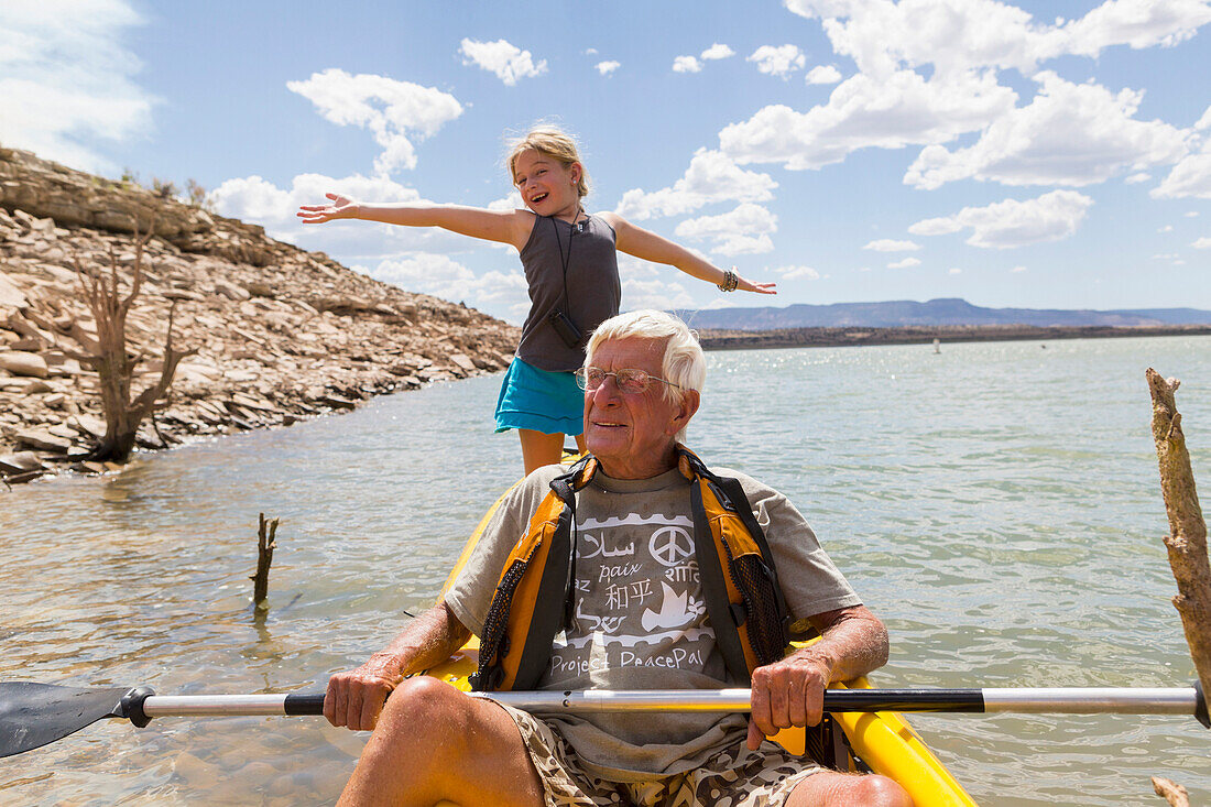 Older Caucasian man rowing kayak with granddaughter, Abiqui, New Mexico, USA
