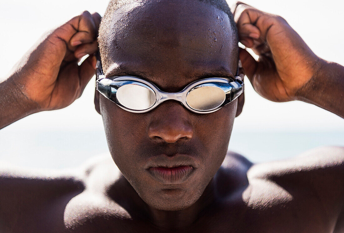 Mixed race swimmer putting on goggles, C1