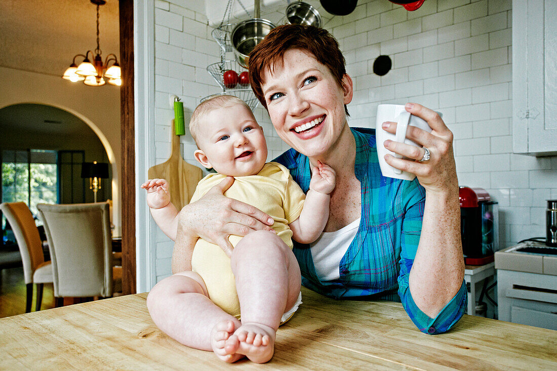 Caucasian mother and baby relaxing in kitchen, C1