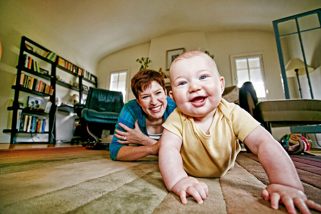 Caucasian mother and baby playing on living room floor, C1