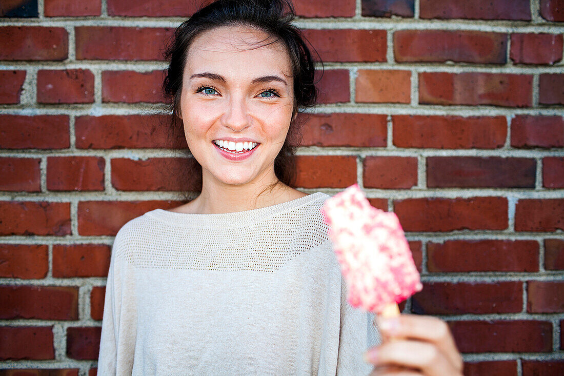 Caucasian woman eating ice cream near red brick wall, Seattle, Washington, United States