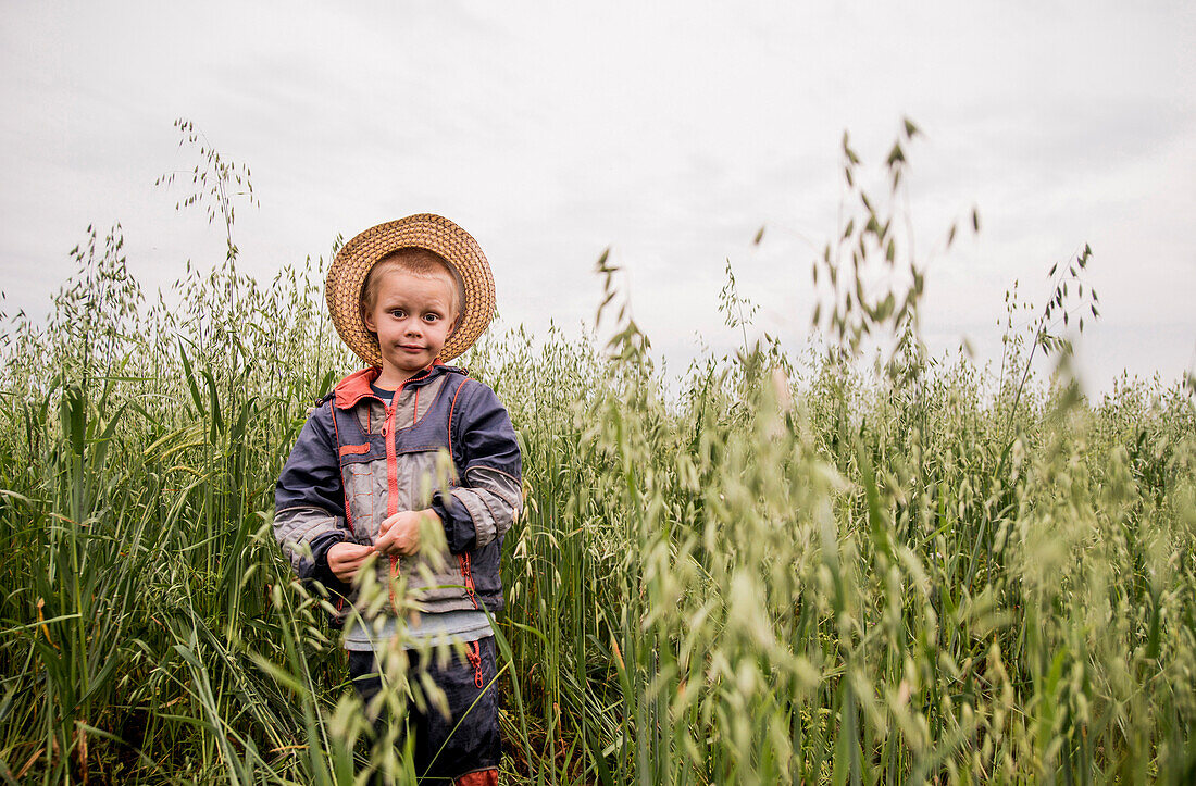 Caucasian boy standing in tall grass in rural field, Ekaterinburg, Ural, Russia