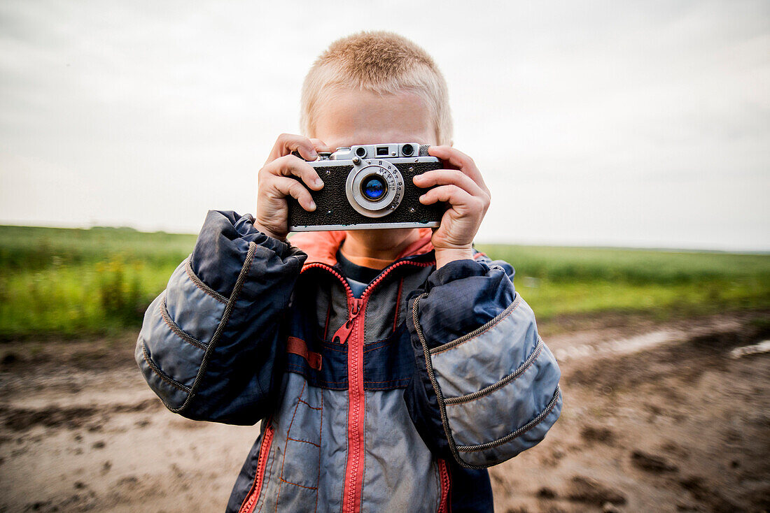Caucasian boy taking photograph in rural field, Ekaterinburg, Ural, Russia