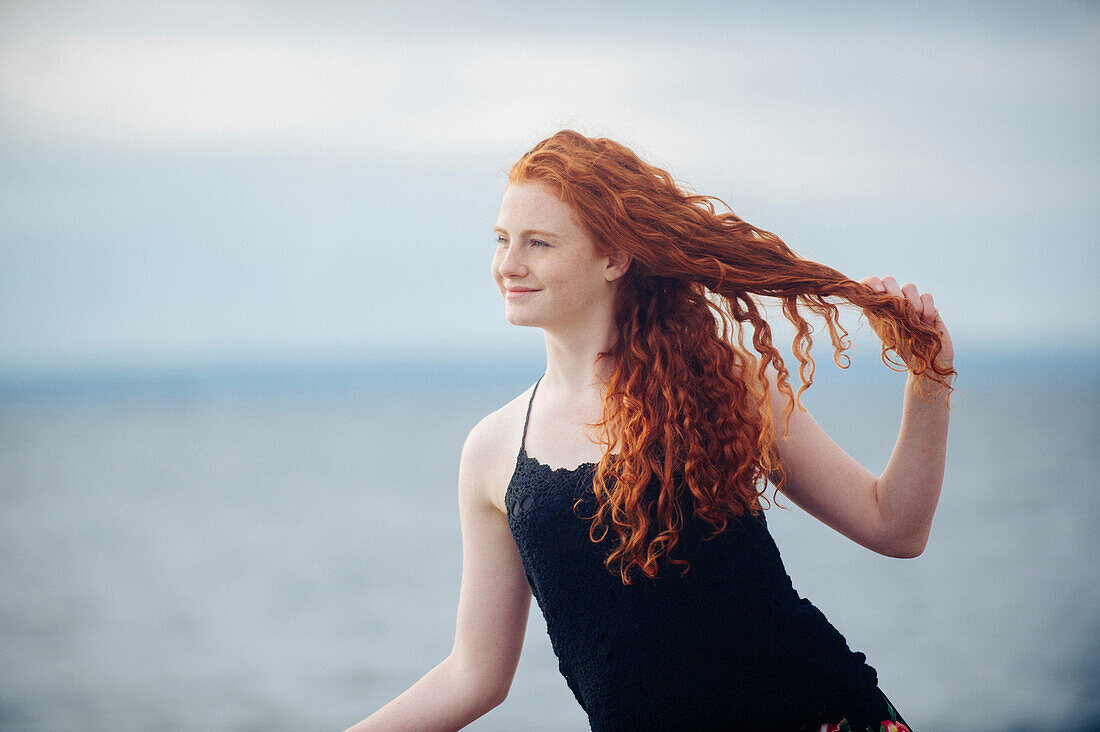 Red haired girl playing with hair on beach, Bainbridge Island, WA, USA