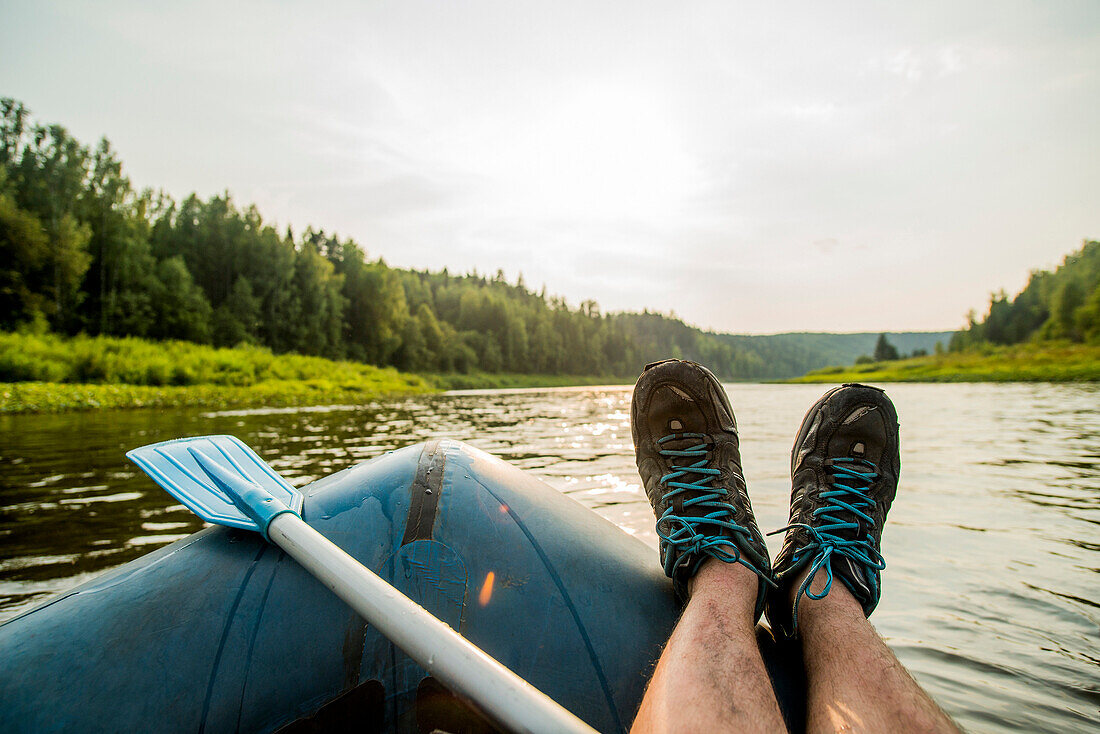 Man resting feet on boat in lake, Ykaterinburg, Swerdlowsk, Russia