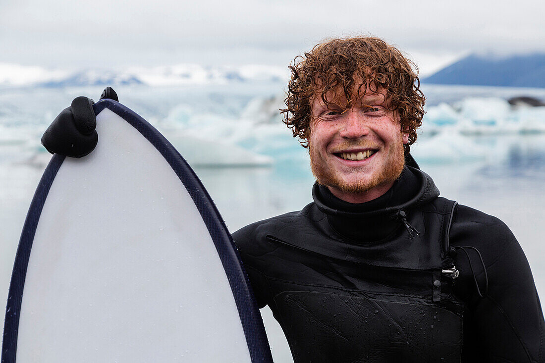 Caucasian surfer holding board near glacial water, Jokulsarlon, Iceland, Iceland