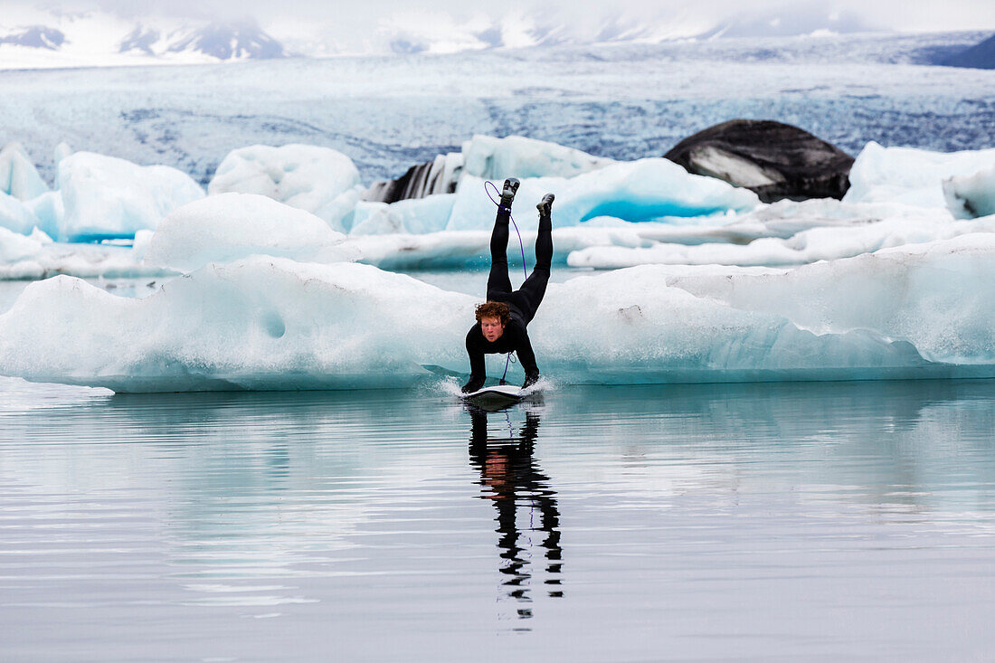 Caucasian surfer leaping on board into glacial water, Jokulsarlon, Iceland, Iceland