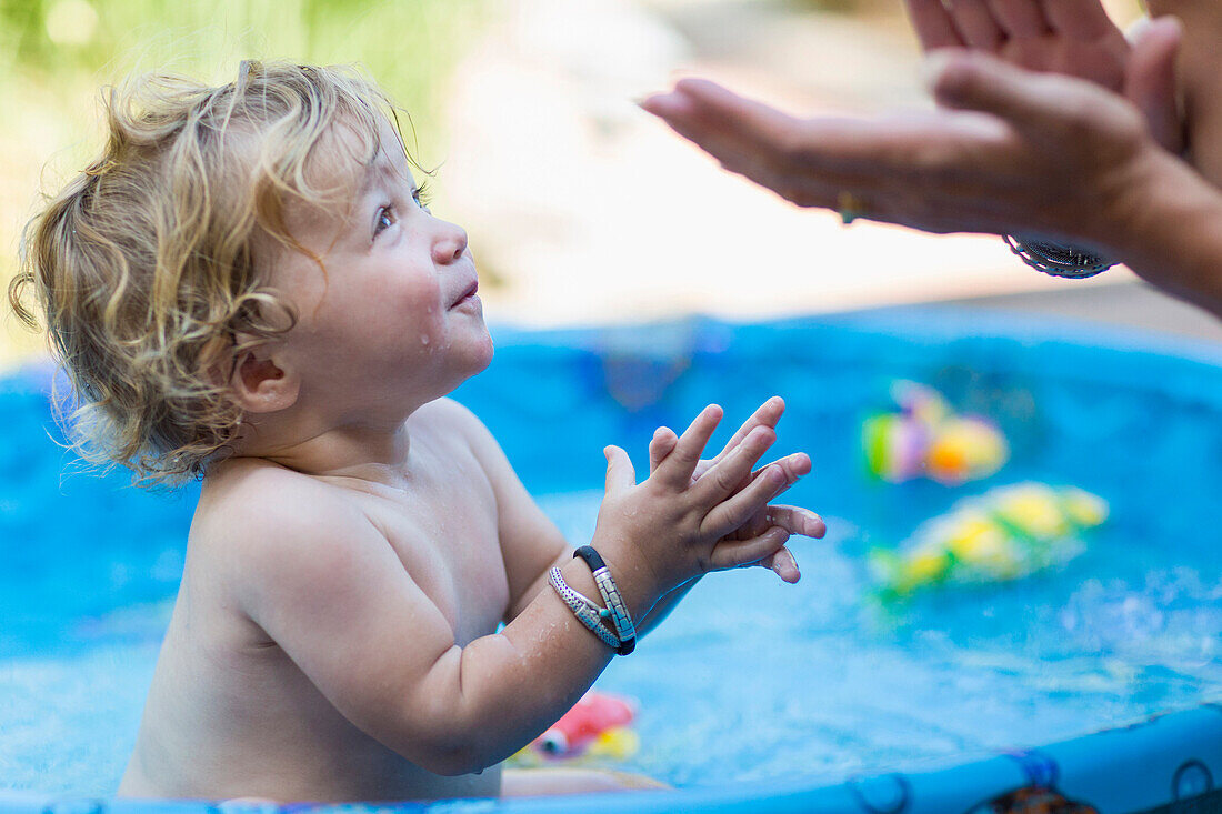 Mother and baby son playing in wading pool, Santa Fe, New Mexico, USA