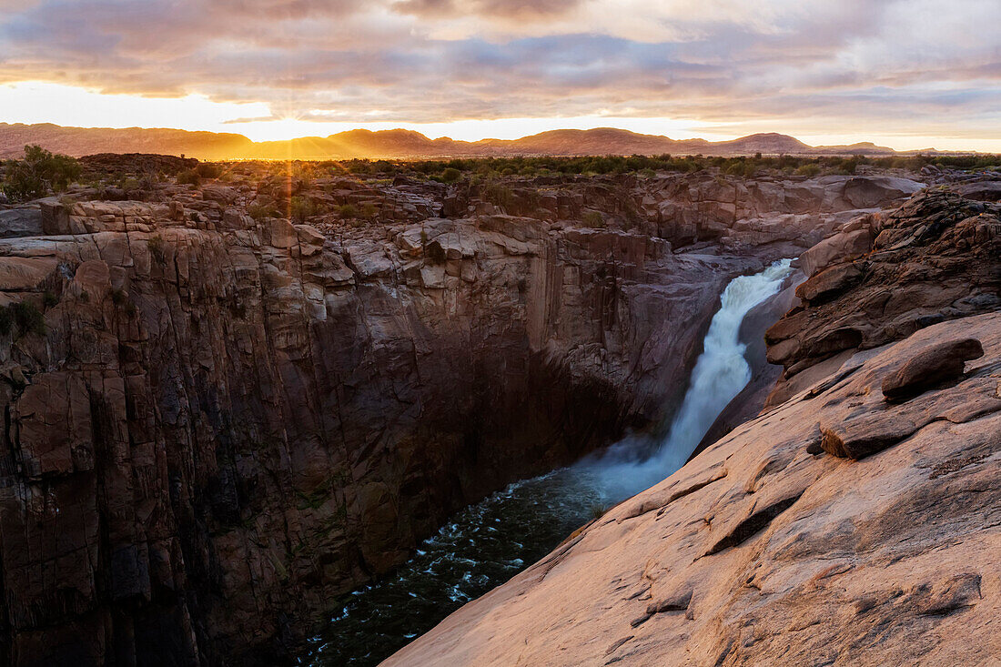 Waterfall flowing over rocky cliffs in remote landscape, Augrabies, Northern Cape, South Africa