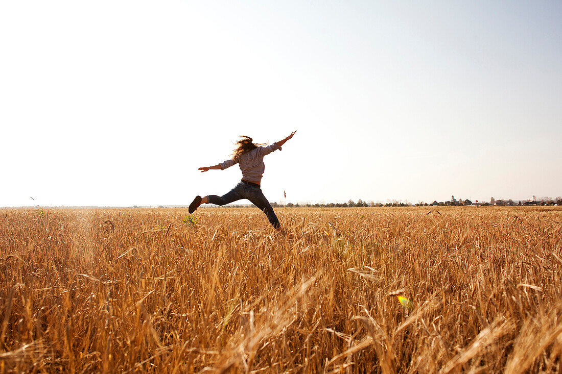 Caucasian woman jumping for joy in rural field, Nizhniy Tagil, Sverdlovsk region, Russia