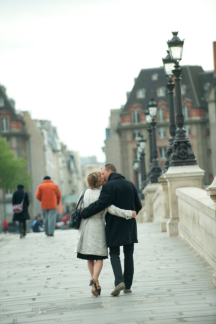 Caucasian couple kissing and walking on bridge, Paris, Paris, France