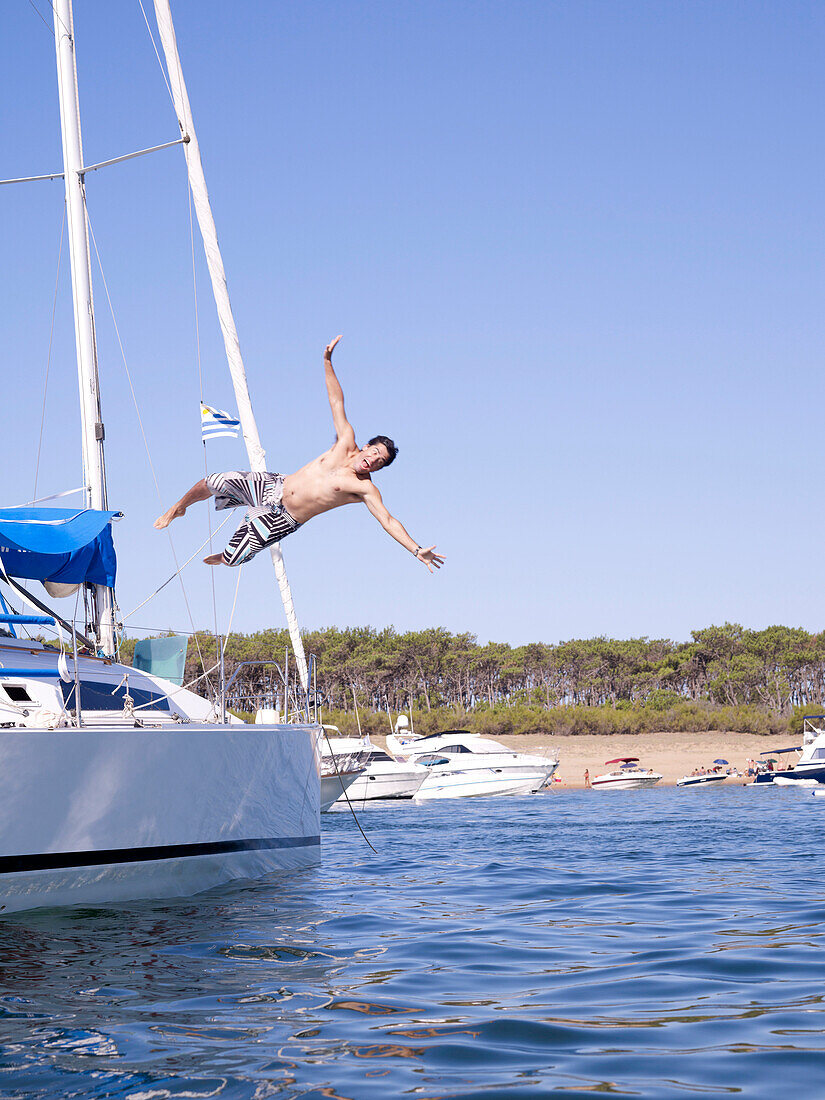 Hispanic man jumping into ocean from sailboat, Punta del Este, Punta del Este, Uruguay