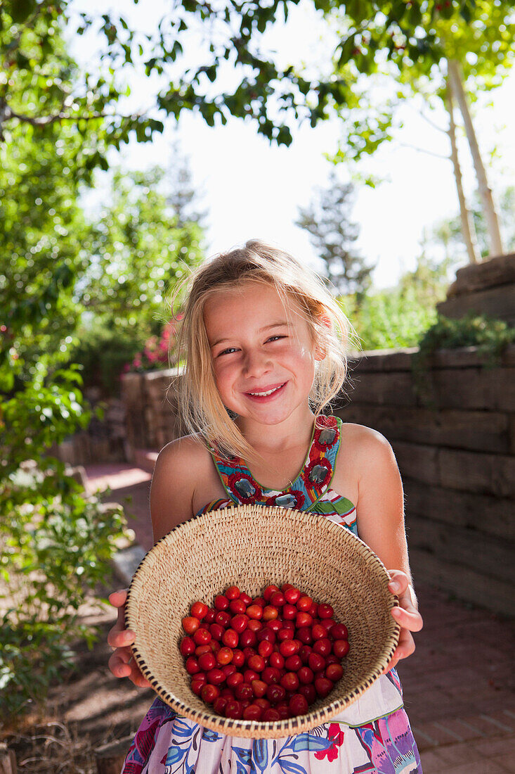 Caucasian girl holding basket of cherries, Santa Fe, New Mexico, USA