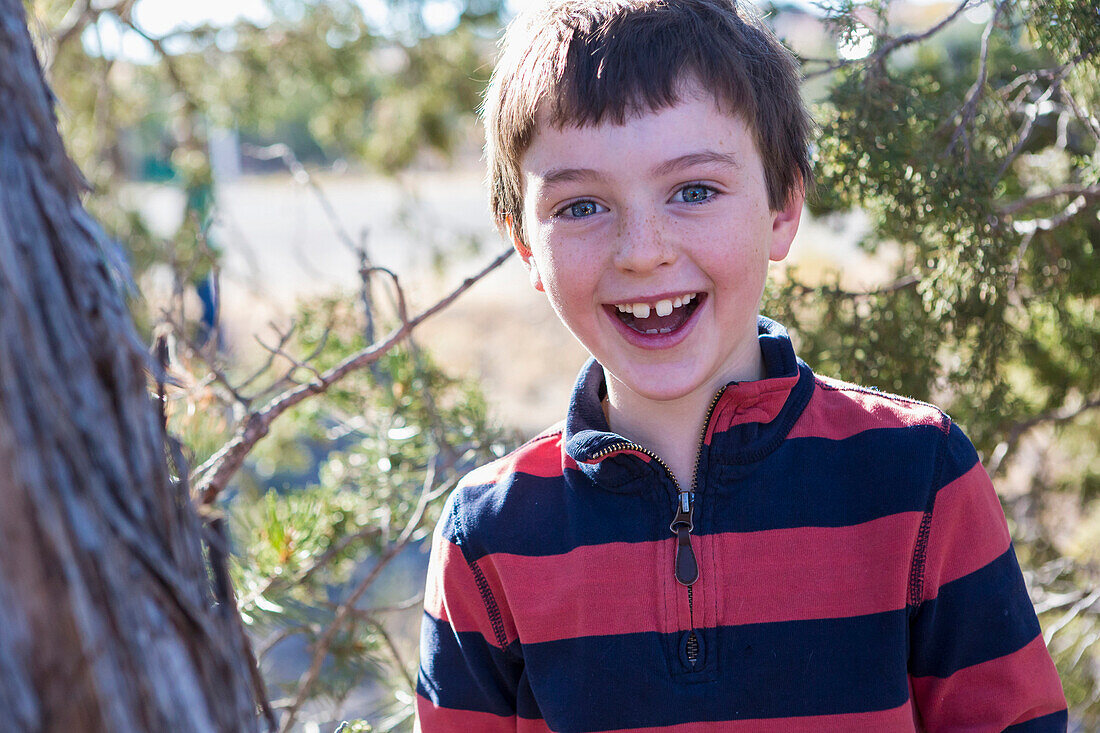 Close up of Caucasian boy smiling near tree, Santa Fe, New Mexico, USA