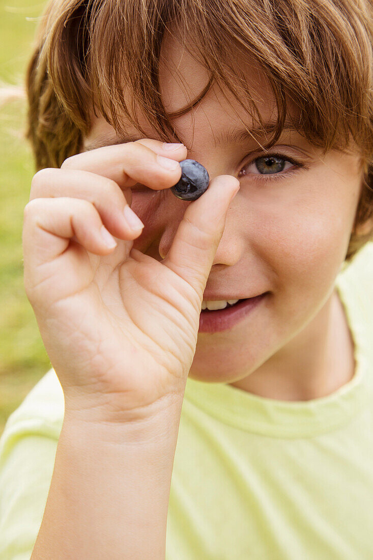 Caucasian boy holding blueberry outdoors, Los Angeles, CA, USA