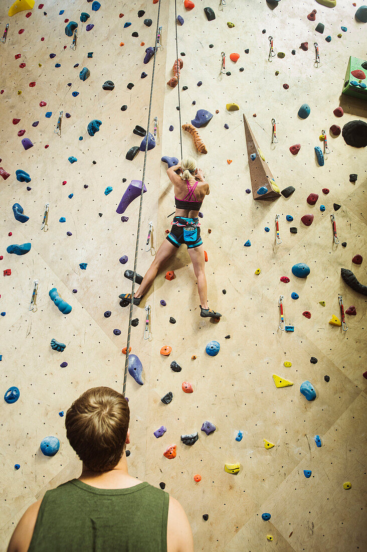 Caucasian man belaying climber at indoor rock wall, Ogden, Utah, USA