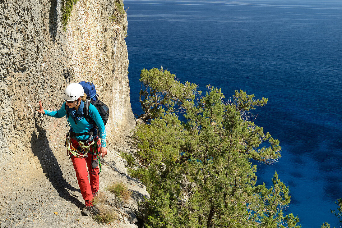 A young woman with trekking gear walking on an exposed ridge in the mountainous coast above the sea, Golfo di Orosei, Selvaggio Blu, Sardinia, Italy, Europe