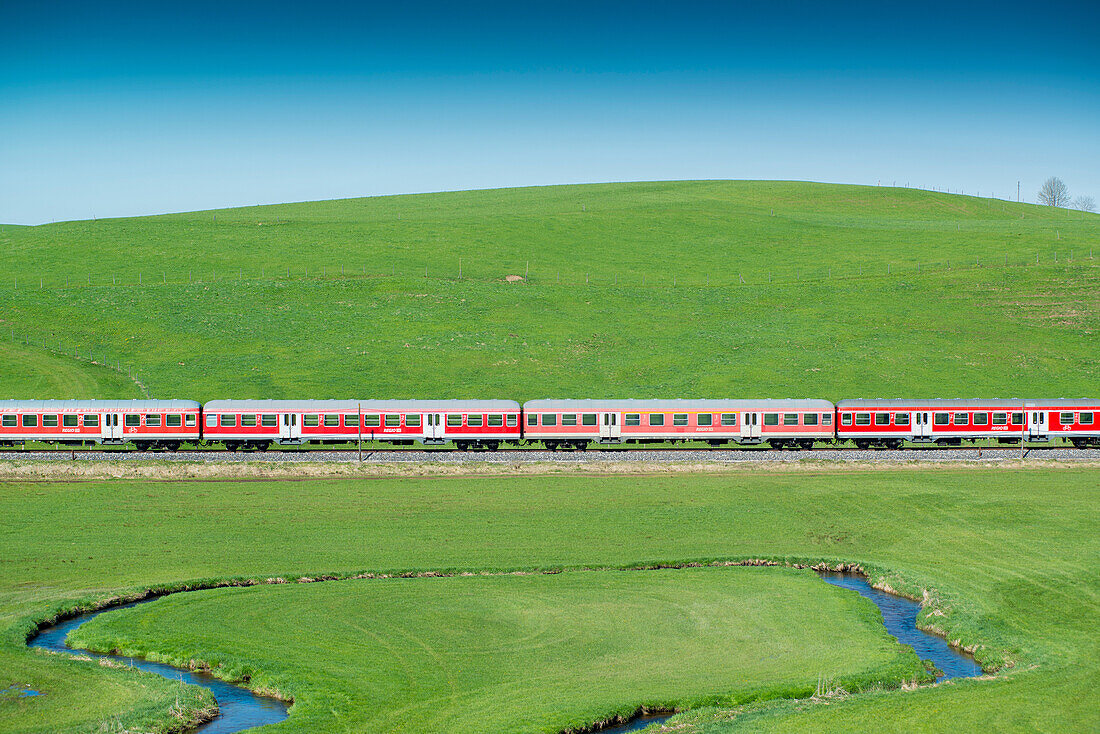 Lengenfelder Wanger Muehlbach meander in Allgaeu. Regional train from Kaufbeuren to Fuessen in the background, Engelbolz, Lengenwang, Allgaeu, Bavaria, Germany