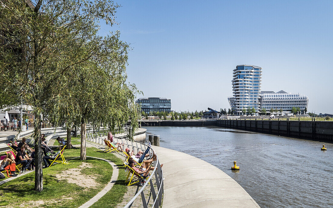 people sitting at Dalmannkai with view to Marco Polo Tower at hafencity in Hamburg, Hamburg, Germany