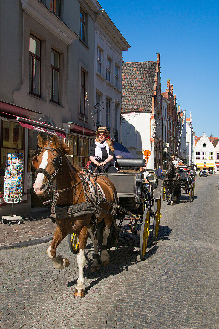 Touristen genießen Fahrt mit Pferdekutsche nahe Marktplatz in der Altstadt, Brügge, Flandern, Belgien, Europa