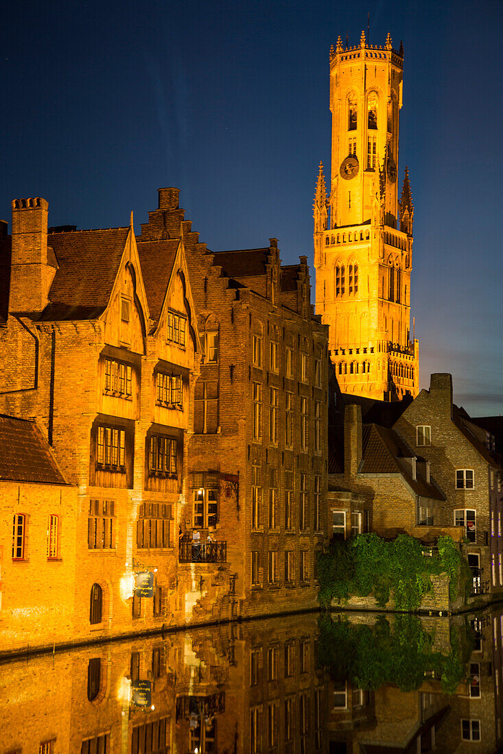 Spiegelung von Belfried und angeleuchteten Gebäuden in einem Kanal in der historischen Altstadt in der Dämmerung, Brügge, Flandern, Belgien, Europa