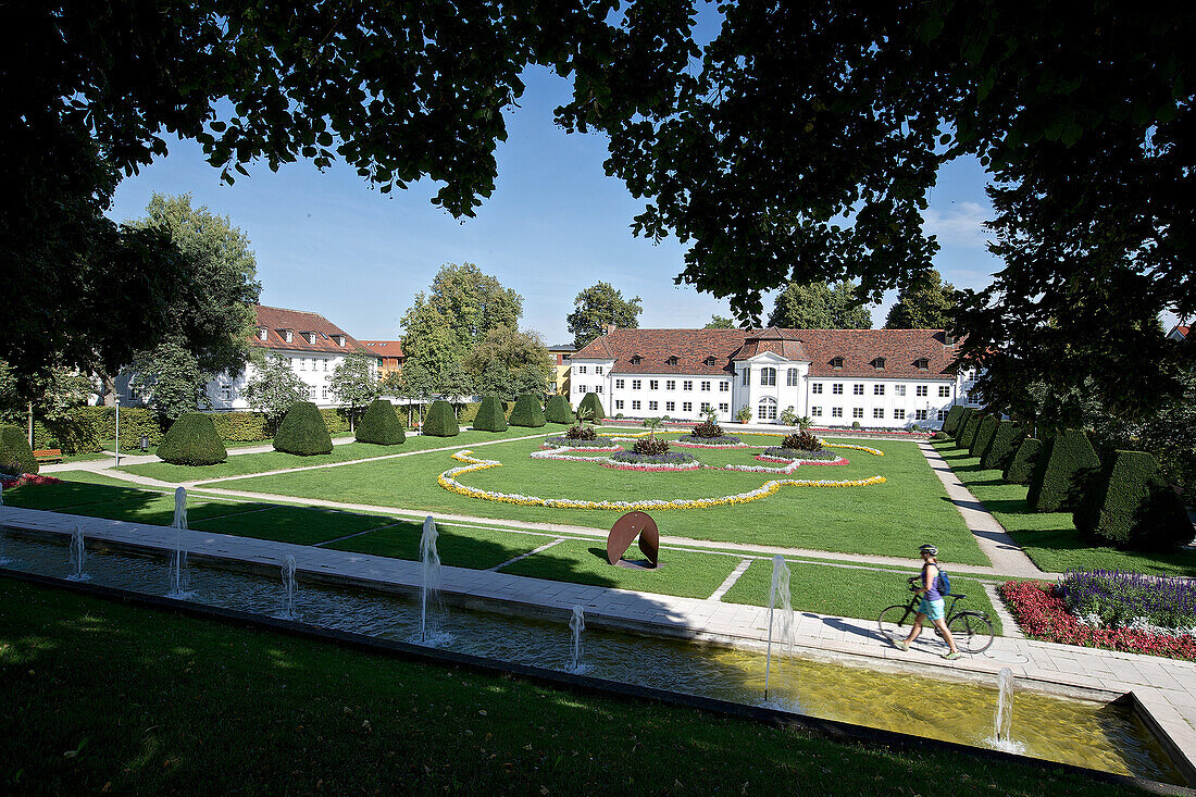 Young woman pushing her bike through a park, Kempten, Bavaria, Germany