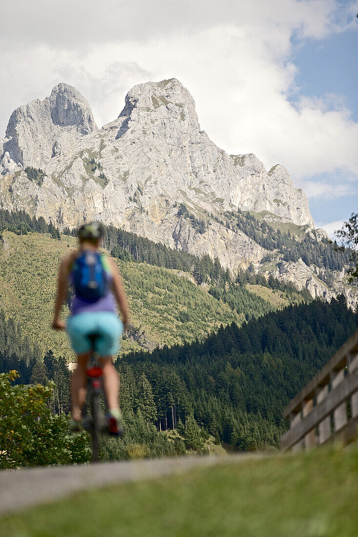 Junge Frau fährt mit ihrem Fahrad in der Nähe der Berge an einem sonnigen Tag, Rote Flöh, Gimpel, Hochwiesler, Tannheimer Tal, Tirol, Österreich