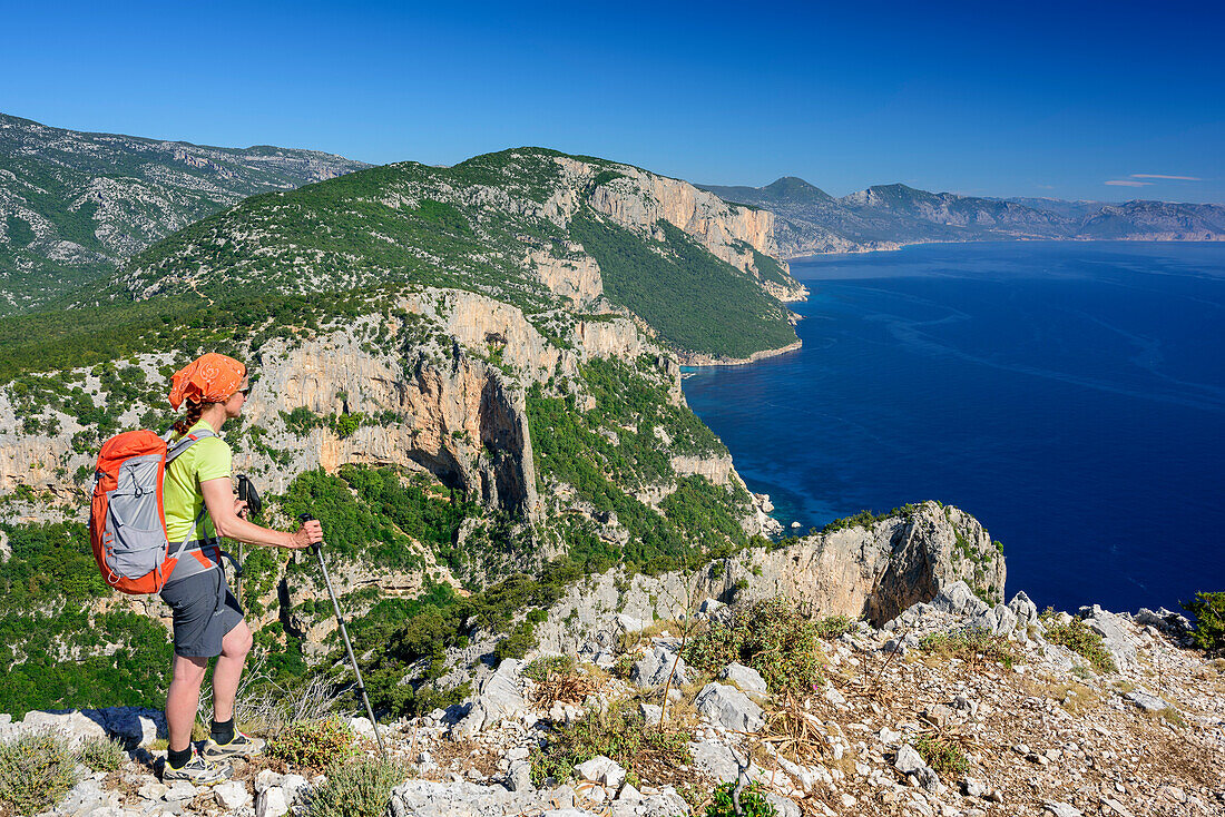 Frau wandert am Selvaggio Blu über Felsgrat mit Blick auf Mittelmeer, Selvaggio Blu, Nationalpark Golfo di Orosei e del Gennargentu, Sardinien, Italien