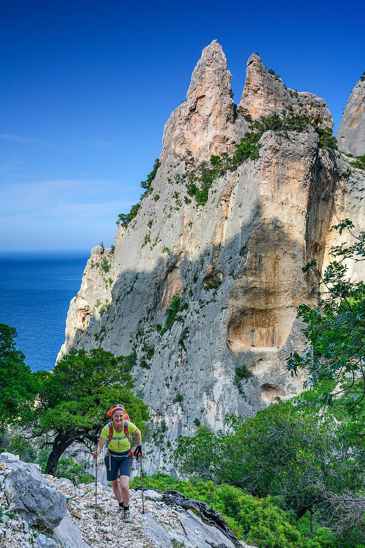 Frau wandert am Selvaggio Blu an Felstürmen vorüber, Selvaggio Blu, Nationalpark Golfo di Orosei e del Gennargentu, Sardinien, Italien