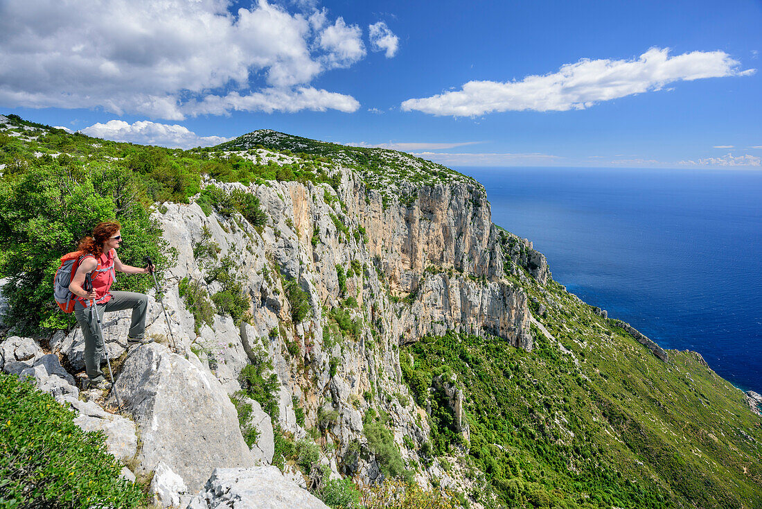 Frau beim Wandern steht an Steilküste blickt auf Golfo di Orosei, Selvaggio Blu, Nationalpark Golfo di Orosei e del Gennargentu, Sardinien, Italien