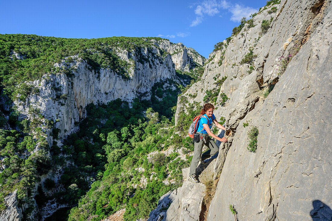 Woman climbing over rock face, Selvaggio Blu, National Park of the Bay of Orosei and Gennargentu, Sardinia, Italy