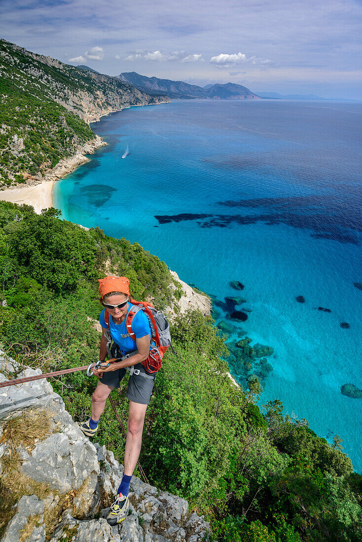 Frau seilt über Felswand ab, Mittelmeer im Hintergrund, Selvaggio Blu, Nationalpark Golfo di Orosei e del Gennargentu, Sardinien, Italien