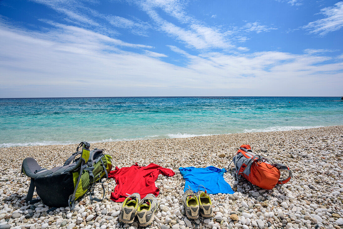 Rucksacks and clothes laying at beach of Cala Sisine at Mediterranean, Cala Sisine, Selvaggio Blu, National Park of the Bay of Orosei and Gennargentu, Sardinia, Italy