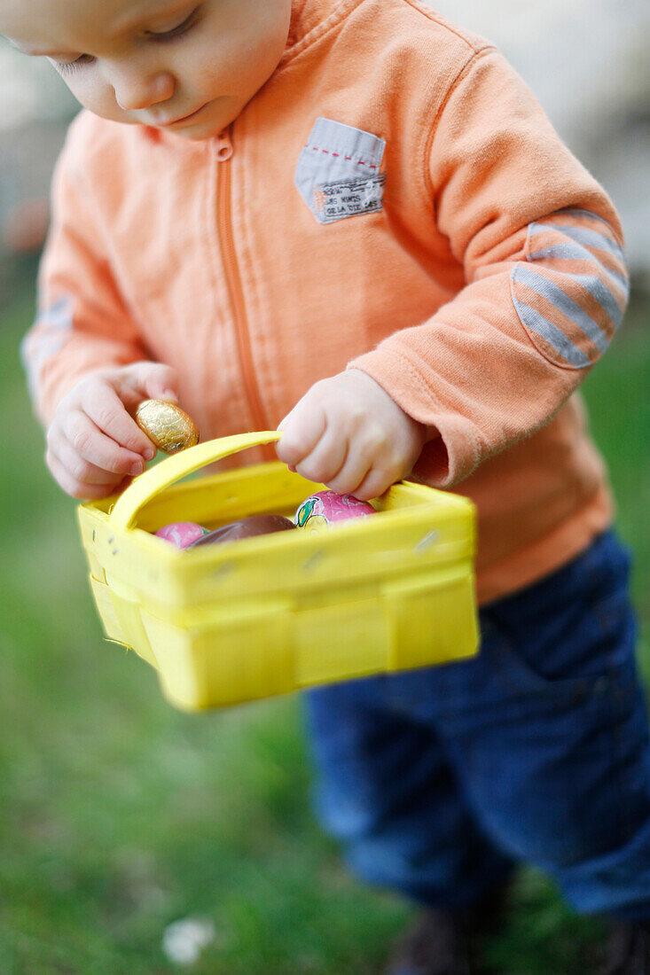 A little boy picking up Easter eggs in the garden