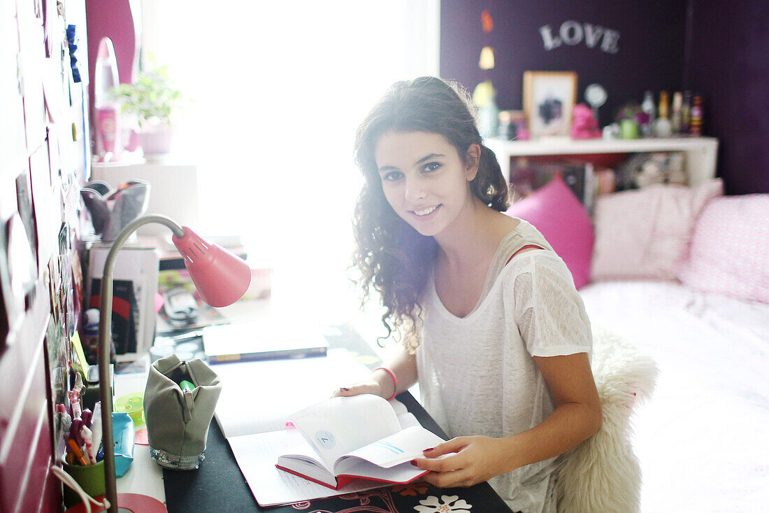 A teenage girl doing her homework in her room