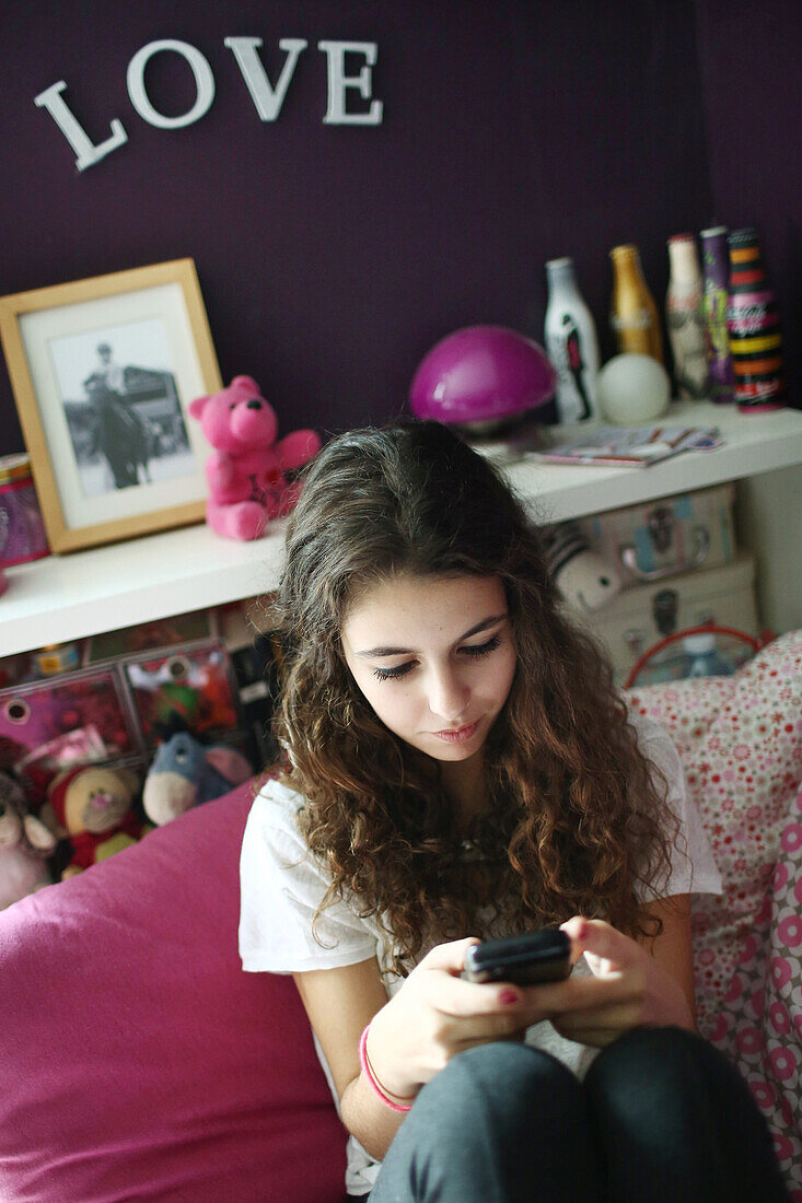 A teenage girl with her cell phone on her bed