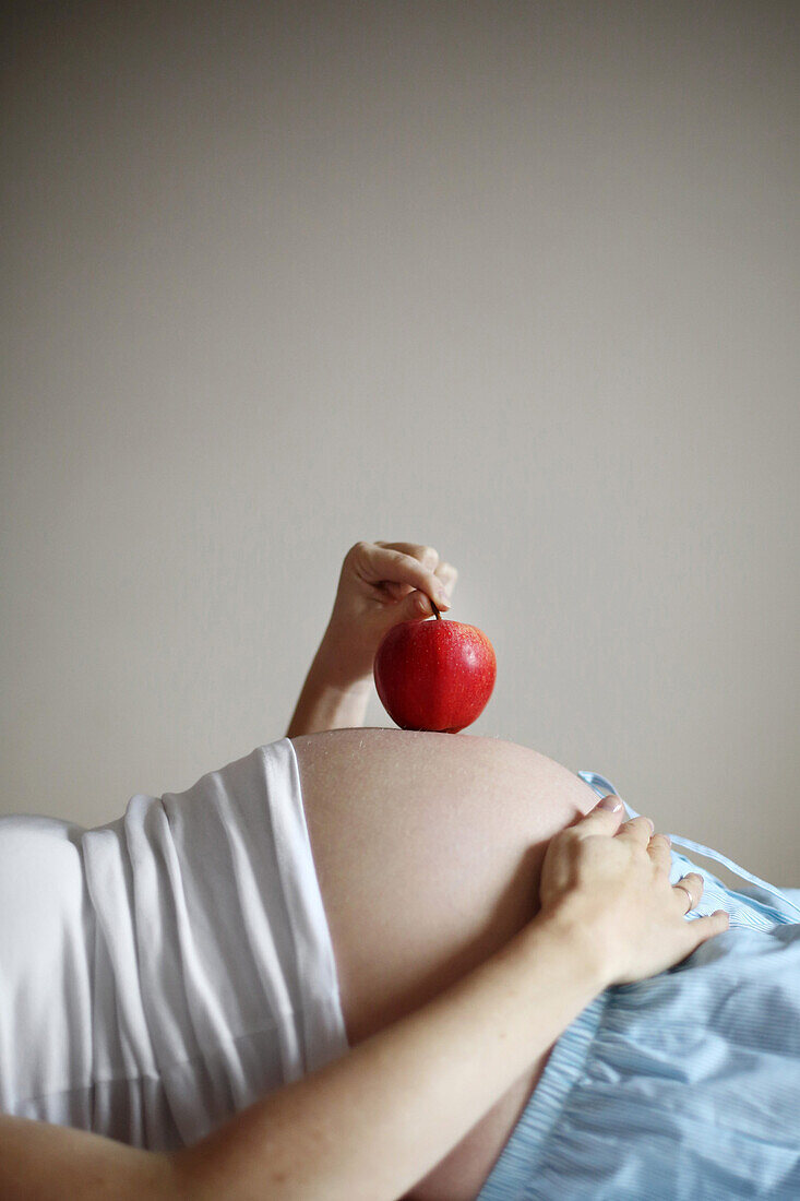 Ein Apfel auf dem Bauch einer im 7. Monat schwangeren Frau