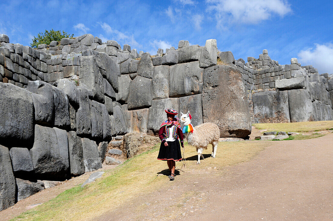 South America, Peru, Cuzco, Sacsayhuaman, wearing some woman in traditional dress carrying a baby walking with a lama