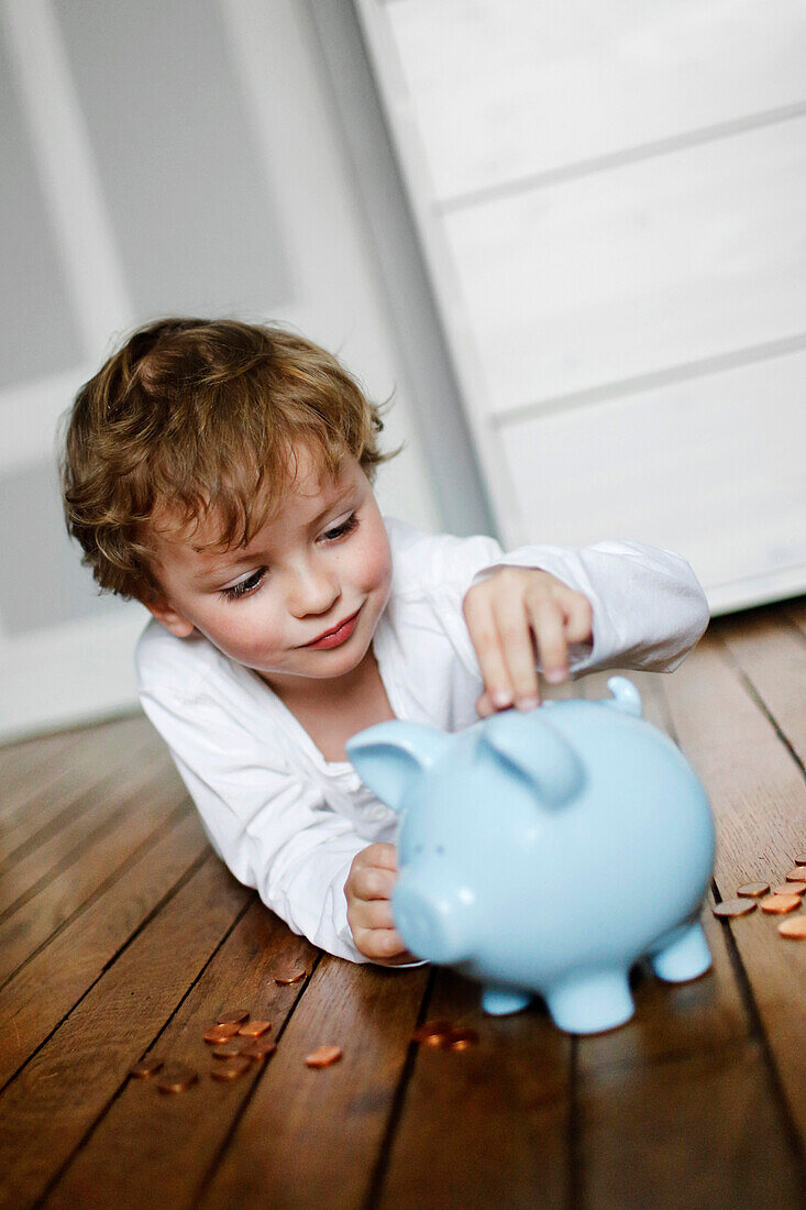 Boy putting coins in piggy bank