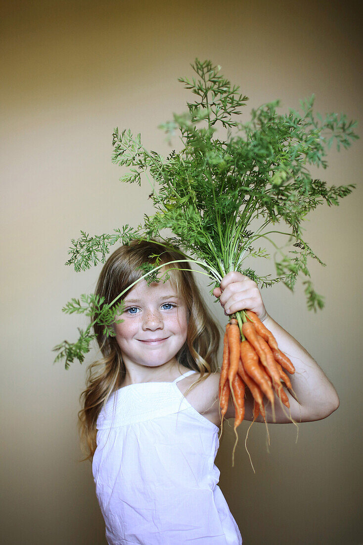 Little girl holding some carrots