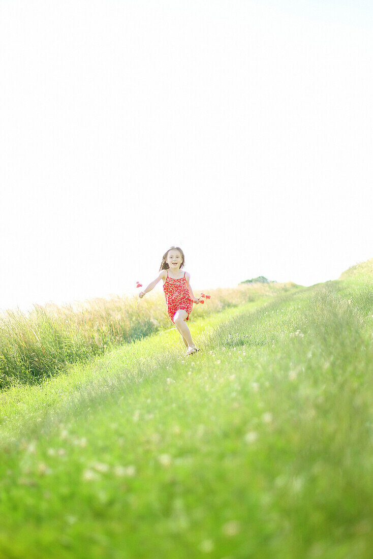 A 7 years girl running with poppies in the hand, on a country lane