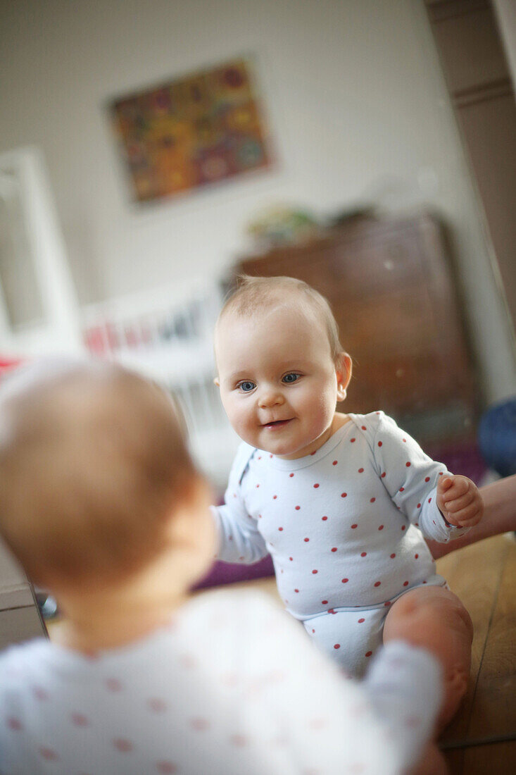 A 10 months baby girl in front of a mirror