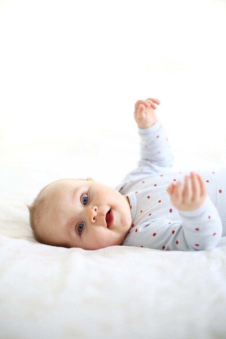 Portrait of a 10 months baby girl lying down on a bed