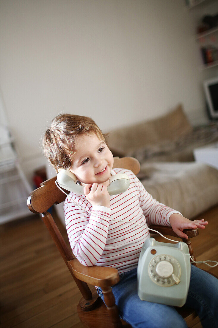 Little boy making a phone call with an old phone