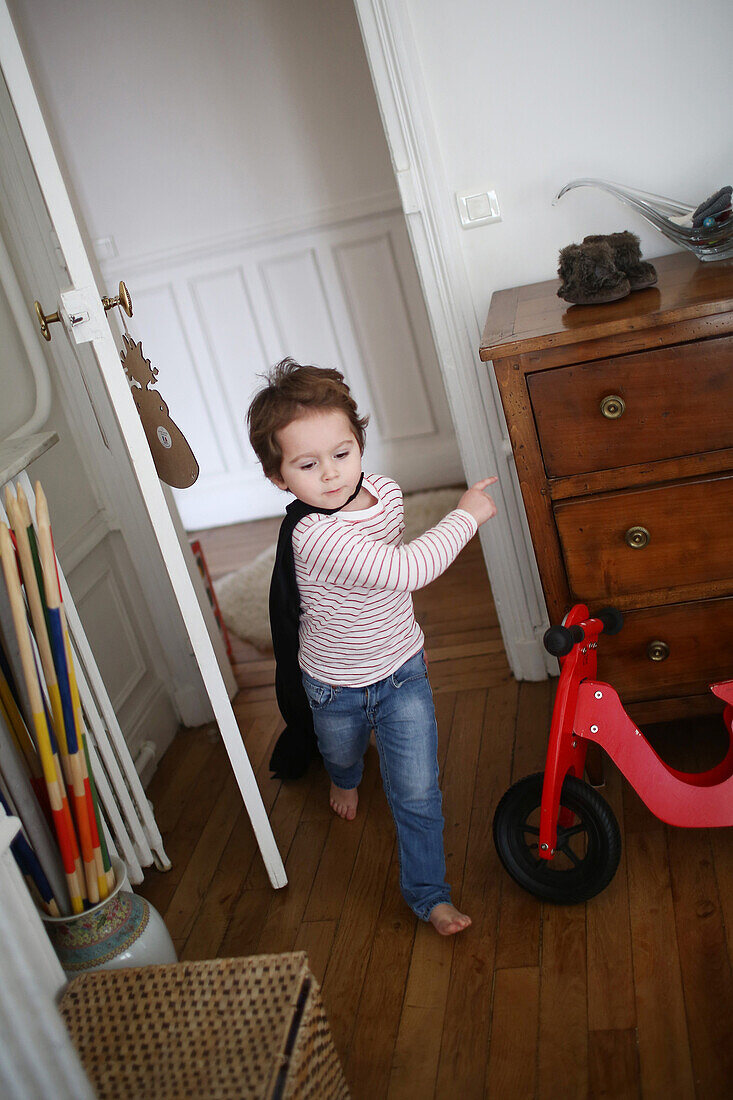 Little boy playing with a black cape, he runs