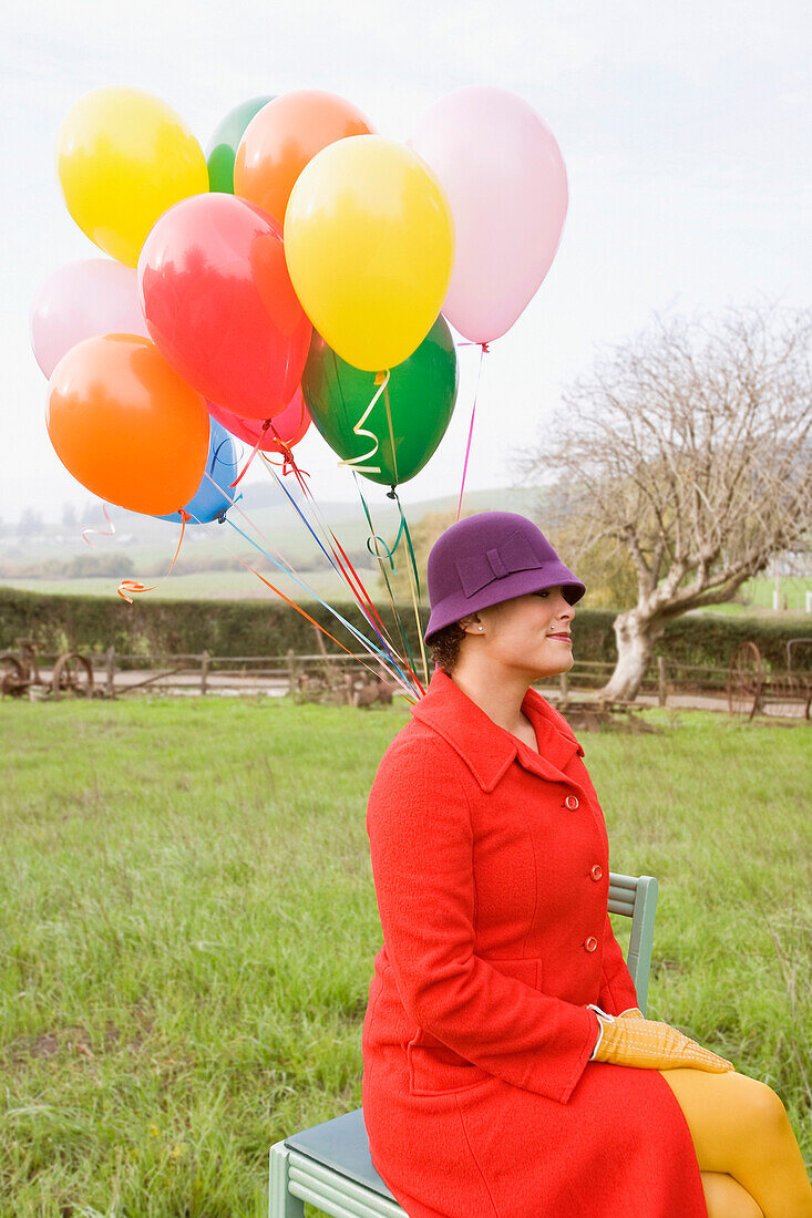 Mixed race woman holding colorful bunch of balloons