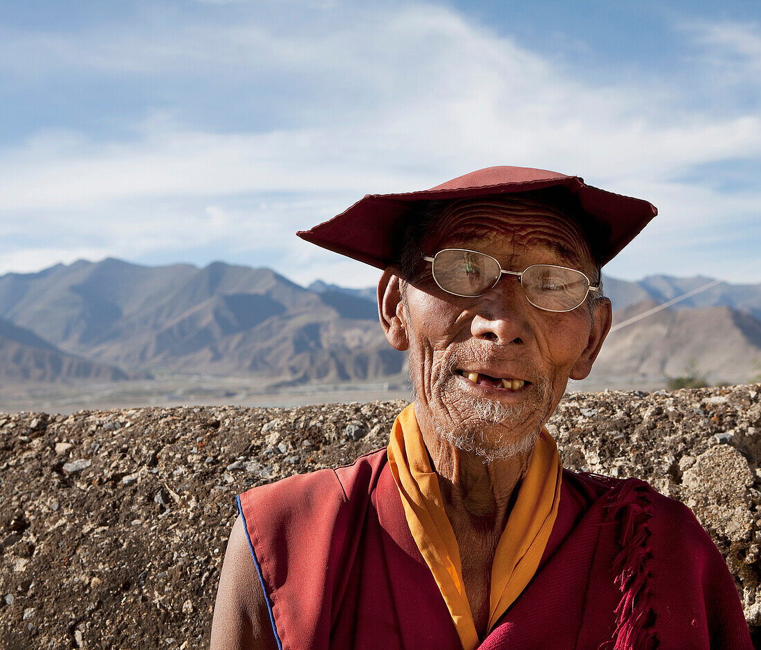 Elderly Tibetan monk in eyeglasses and hat