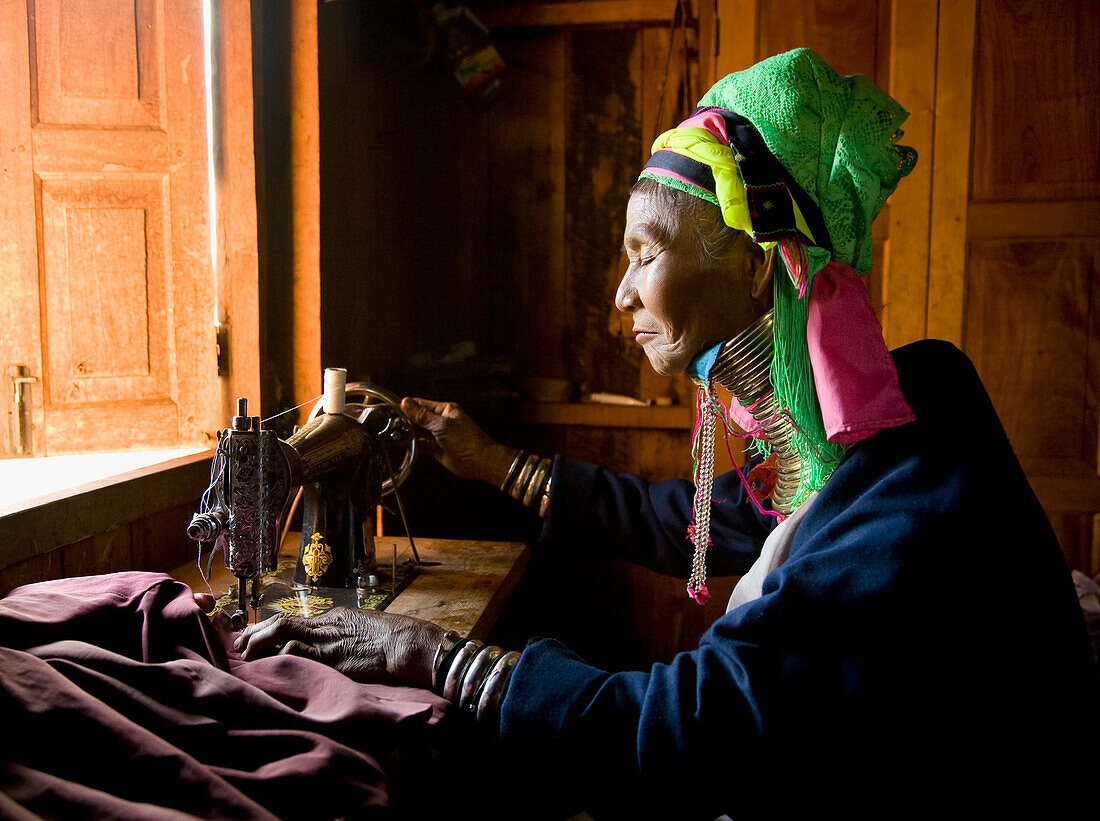 Burmese woman wearing neck rings at sewing machine
