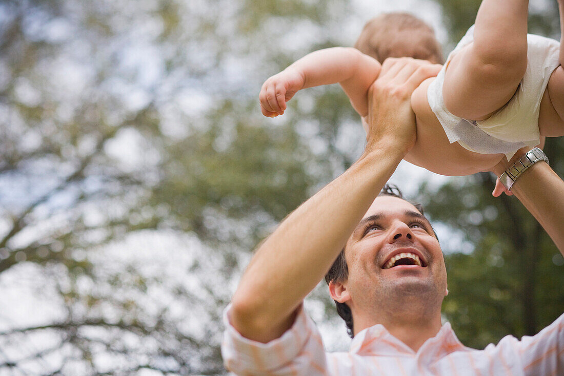 Hispanic father lifting baby