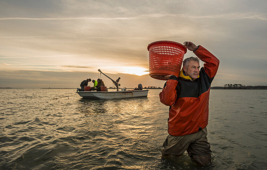 Caucasian fisherman carrying basket in water